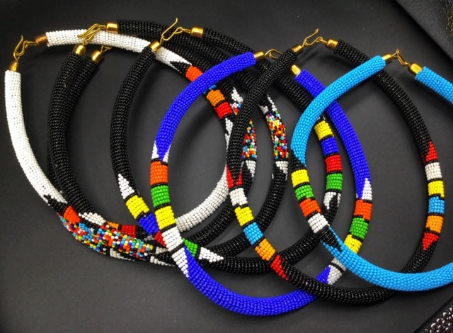 Wear the epitome of Kenya style with The Bintiah necklace. This necklace is handmade using colorful seed beads that are intricately and tightly wrapped around a solid piece fo make a stunning statement with any outfit. multiple colors pictures