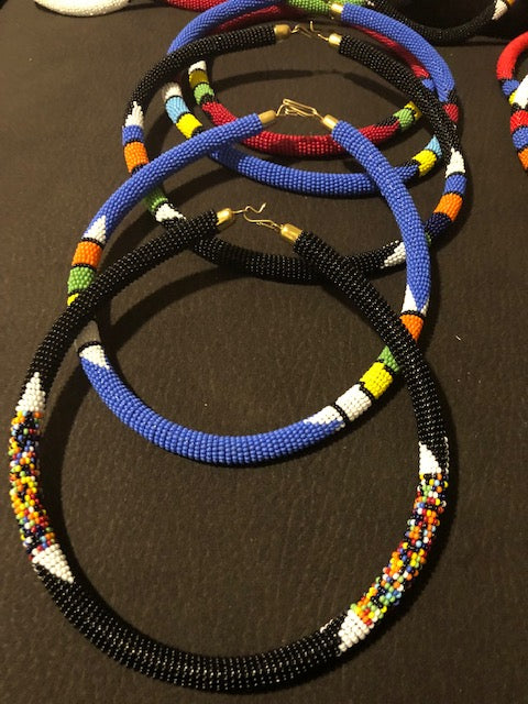 Wear the epitome of Kenya style with The Bintiah necklace. This necklace is handmade using colorful seed beads that are intricately and tightly wrapped around a solid piece fo make a stunning statement with any outfit. Multiple colors pictured.