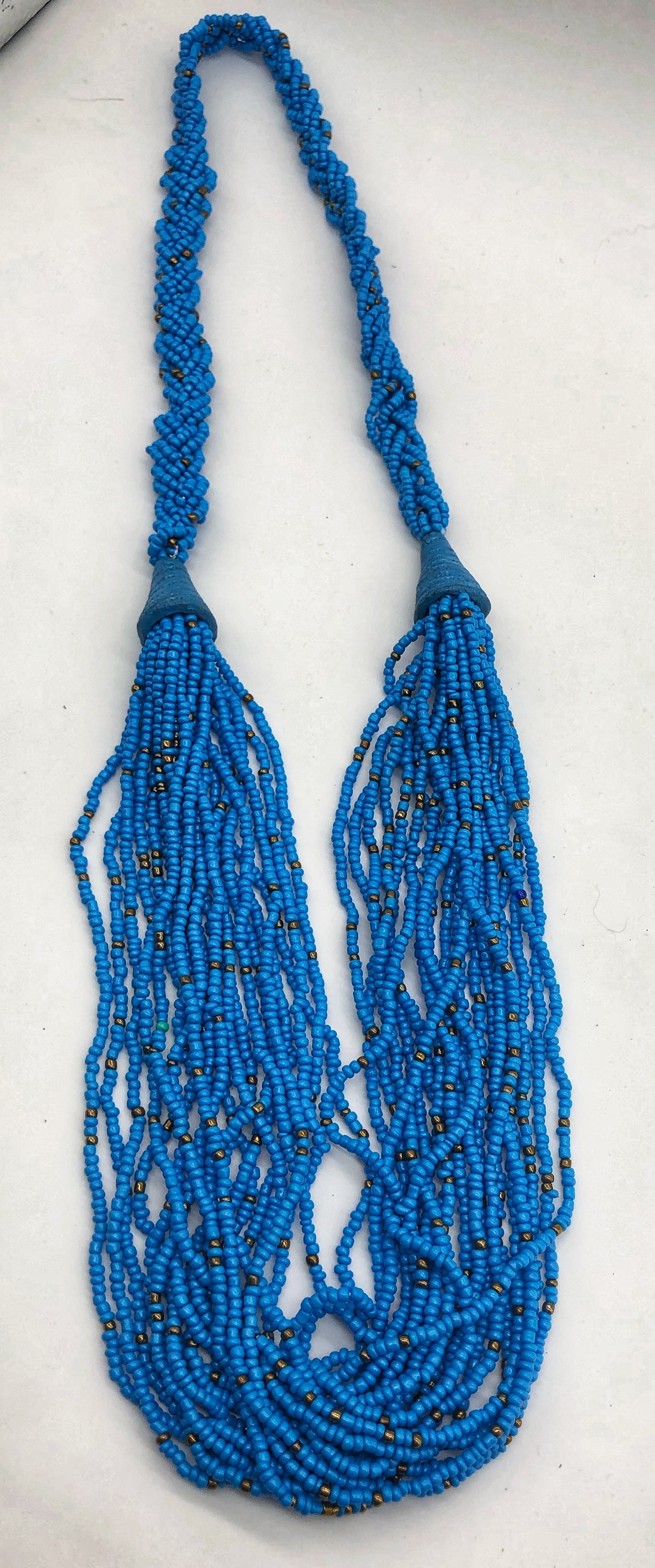 Make a statement with this beautiful handmade seed bead necklace. Styled with braided beads around the neck flowing into a loose styled design. Turquoise with gold bead accent.