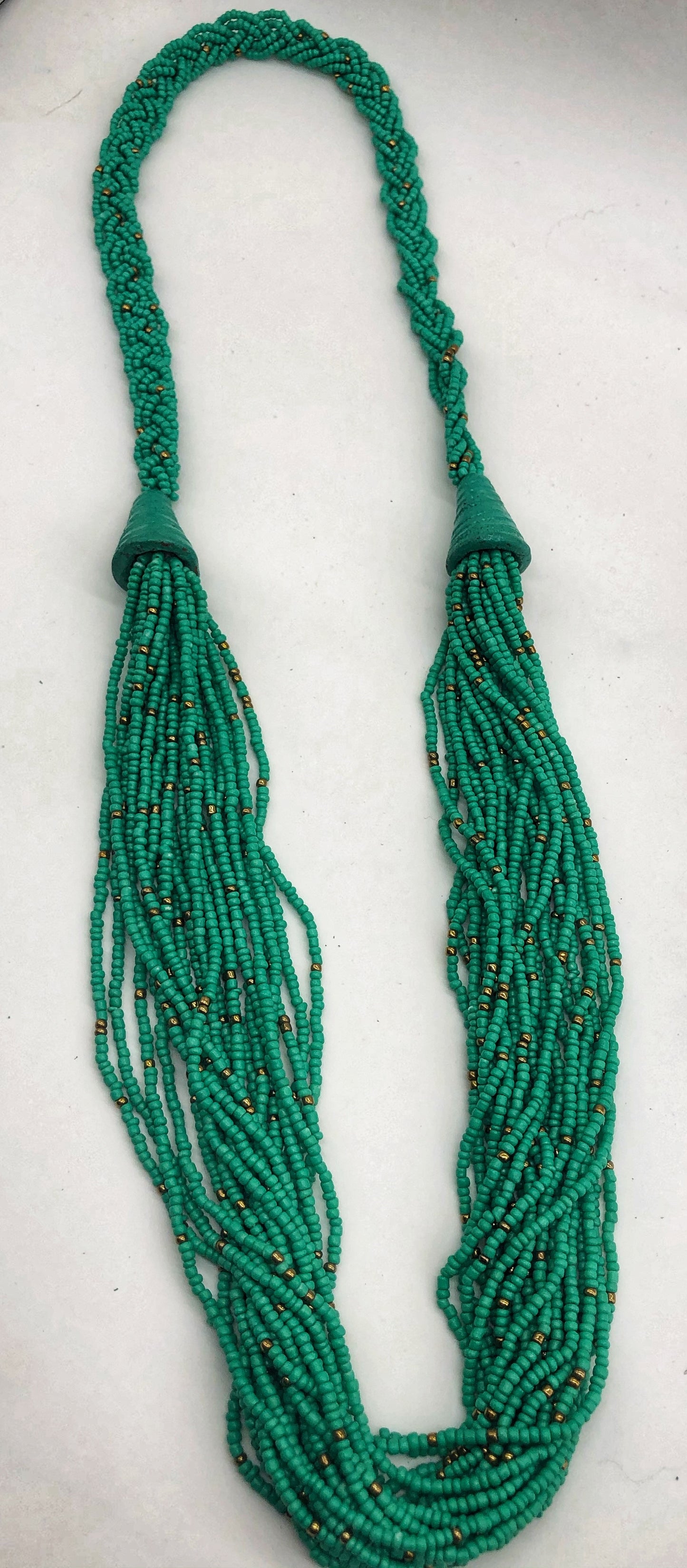 Make a statement with this beautiful handmade seed bead necklace. Styled with braided beads around the neck flowing into a loose styled design. Aqua with gold bead accent
