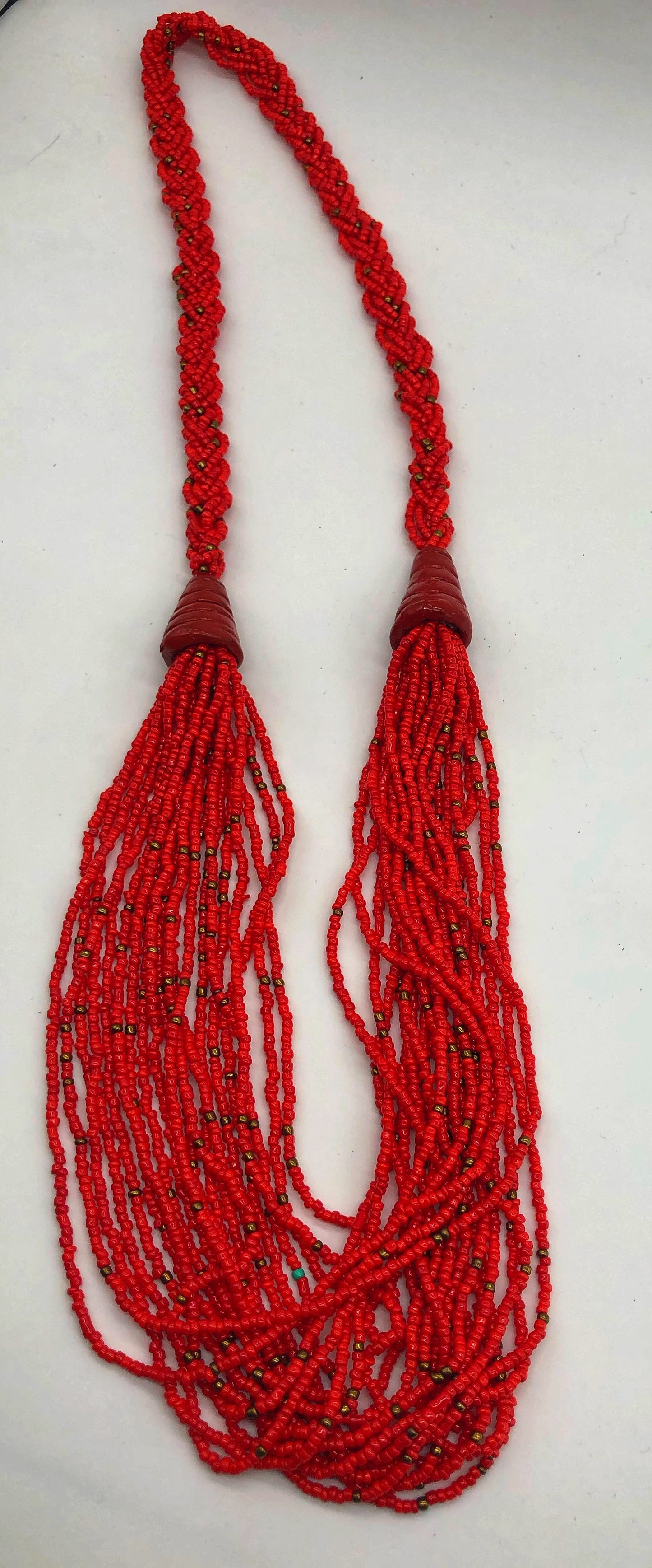 Make a statement with this beautiful handmade seed bead necklace. Styled with braided beads around the neck flowing into a loose styled design. Red with gold bead accent