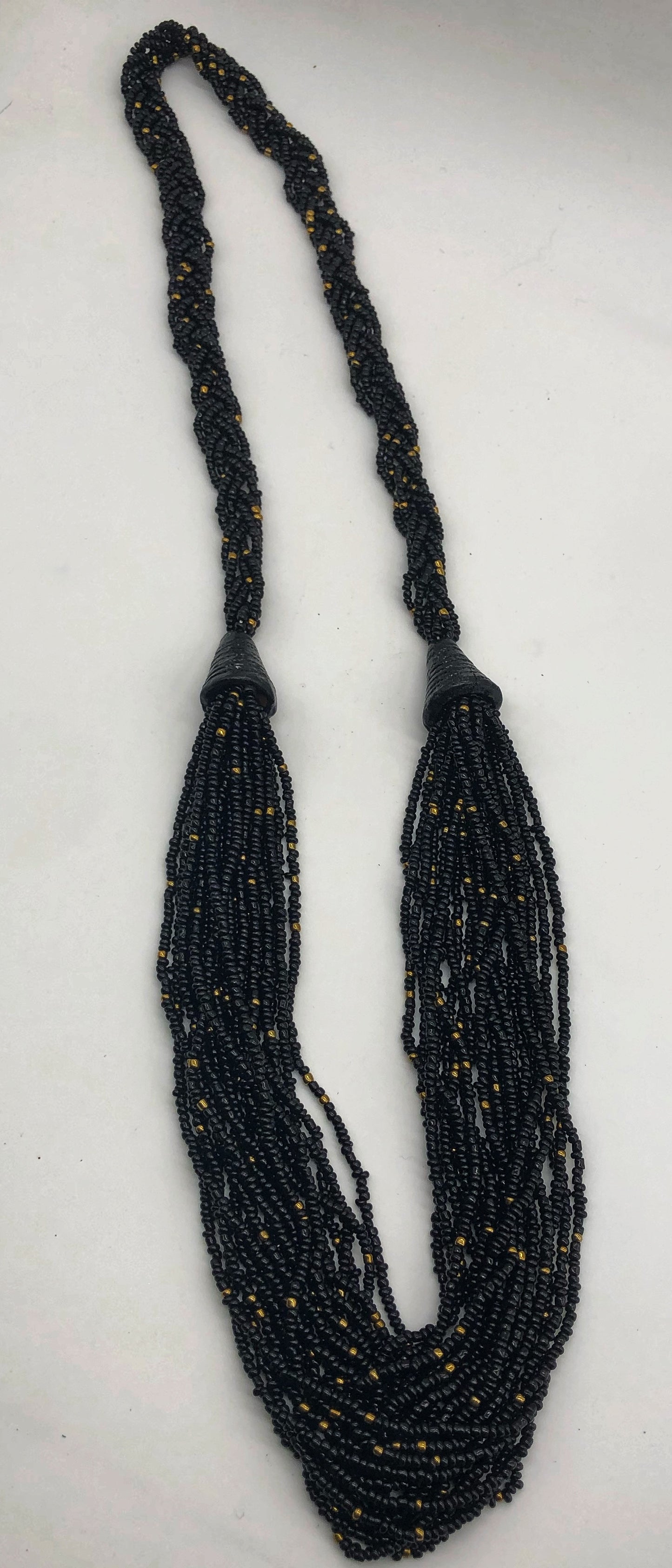 Make a statement with this beautiful handmade seed bead necklace. Styled with braided beads around the neck flowing into a loose styled design. Black with gold bead accent