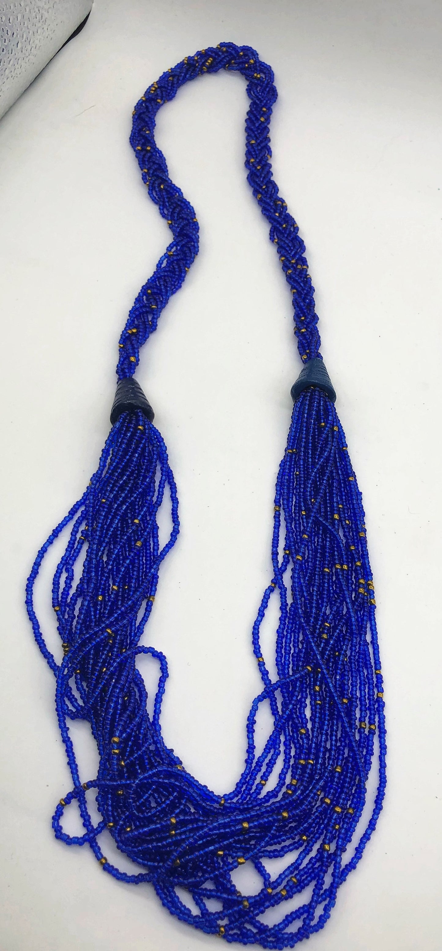 Make a statement with this beautiful handmade seed bead necklace. Styled with braided beads around the neck flowing into a loose styled design. Royal blue with gold bead accent