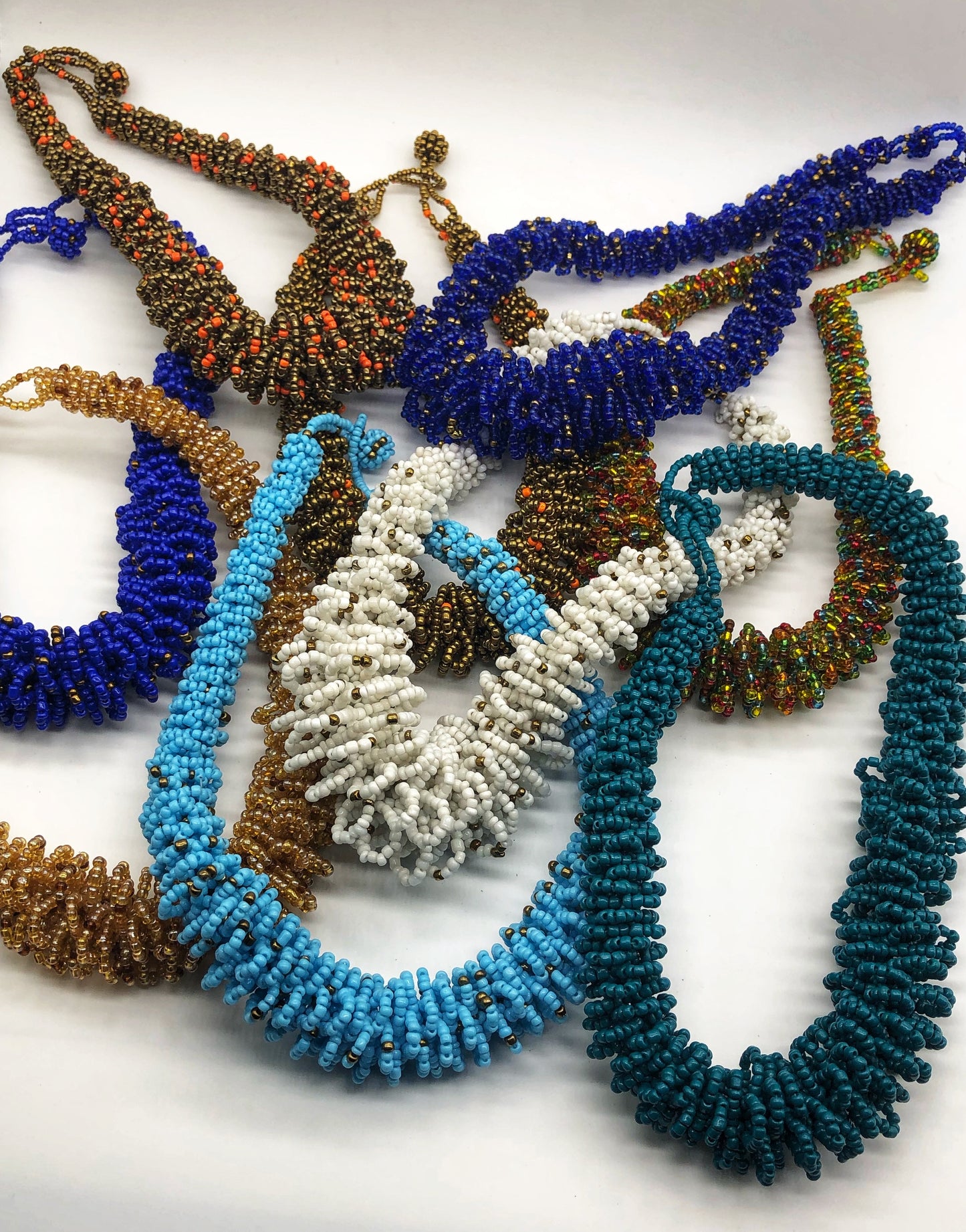 Stand out in style with this beautiful handmade loop bead style necklace. Hover over the photo to see the detail of how the beads are made into a loop design. Thoughtfully designed for style and stand out fashion. Approximately 18" end to end. Multiple colors shown.