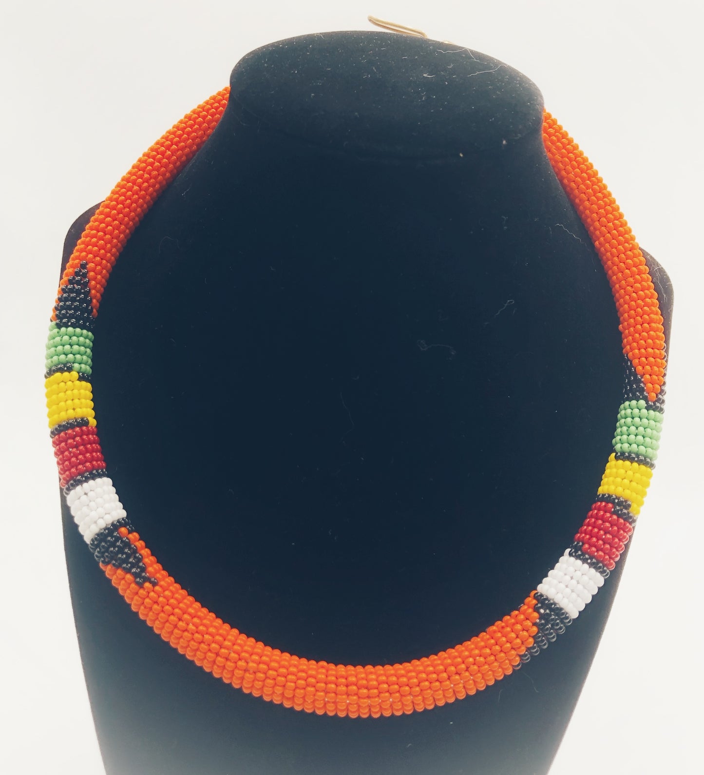 Wear the epitome of Kenya style with The Bintiah necklace. This necklace is handmade using colorful seed beads that are intricately and tightly wrapped around a solid piece fo make a stunning statement with any outfit. Orange with colorful bead accent