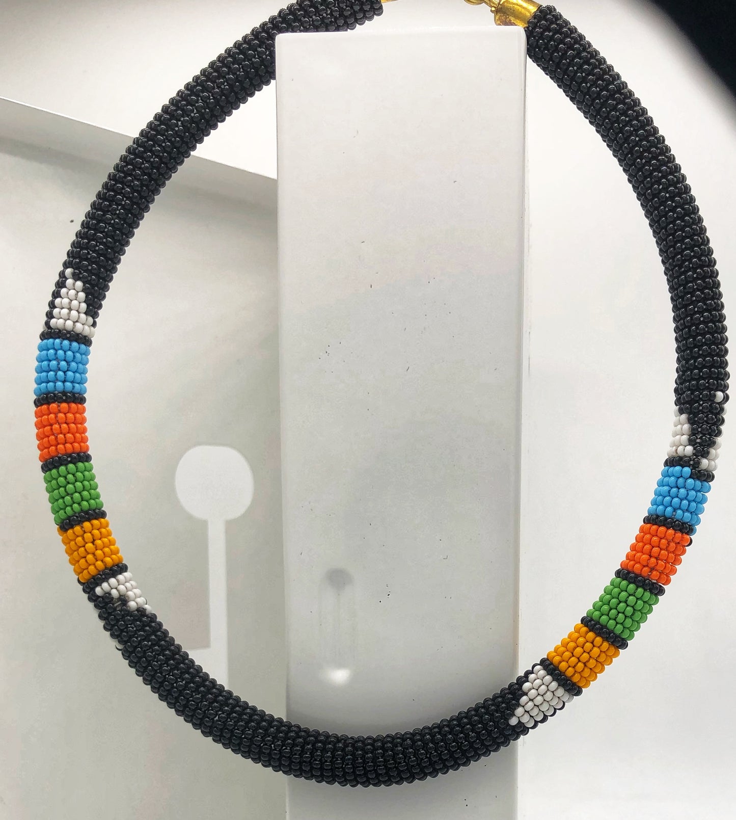 Wear the epitome of Kenya style with The Bintiah necklace. This necklace is handmade using colorful seed beads that are intricately and tightly wrapped around a solid piece fo make a stunning statement with any outfit. Black with colorful bead accent.