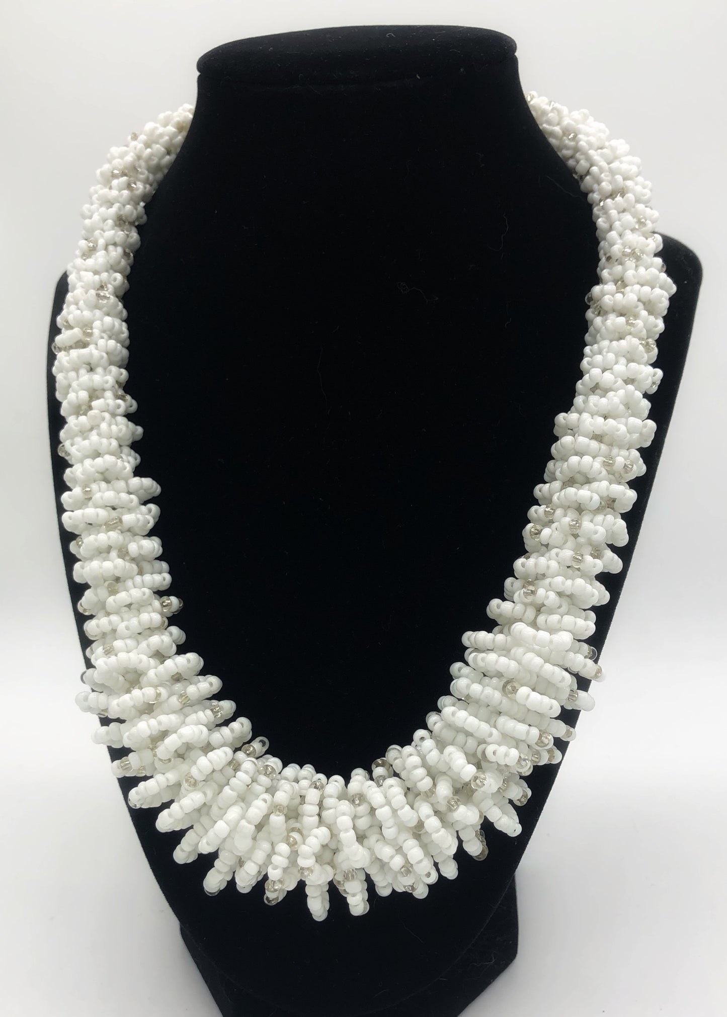 Stand out in style with this beautiful handmade loop bead style necklace. Hover over the photo to see the detail of how the beads are made into a loop design. Thoughtfully designed for style and stand out fashion. Approximately 18" end to end. White with silver bead accent