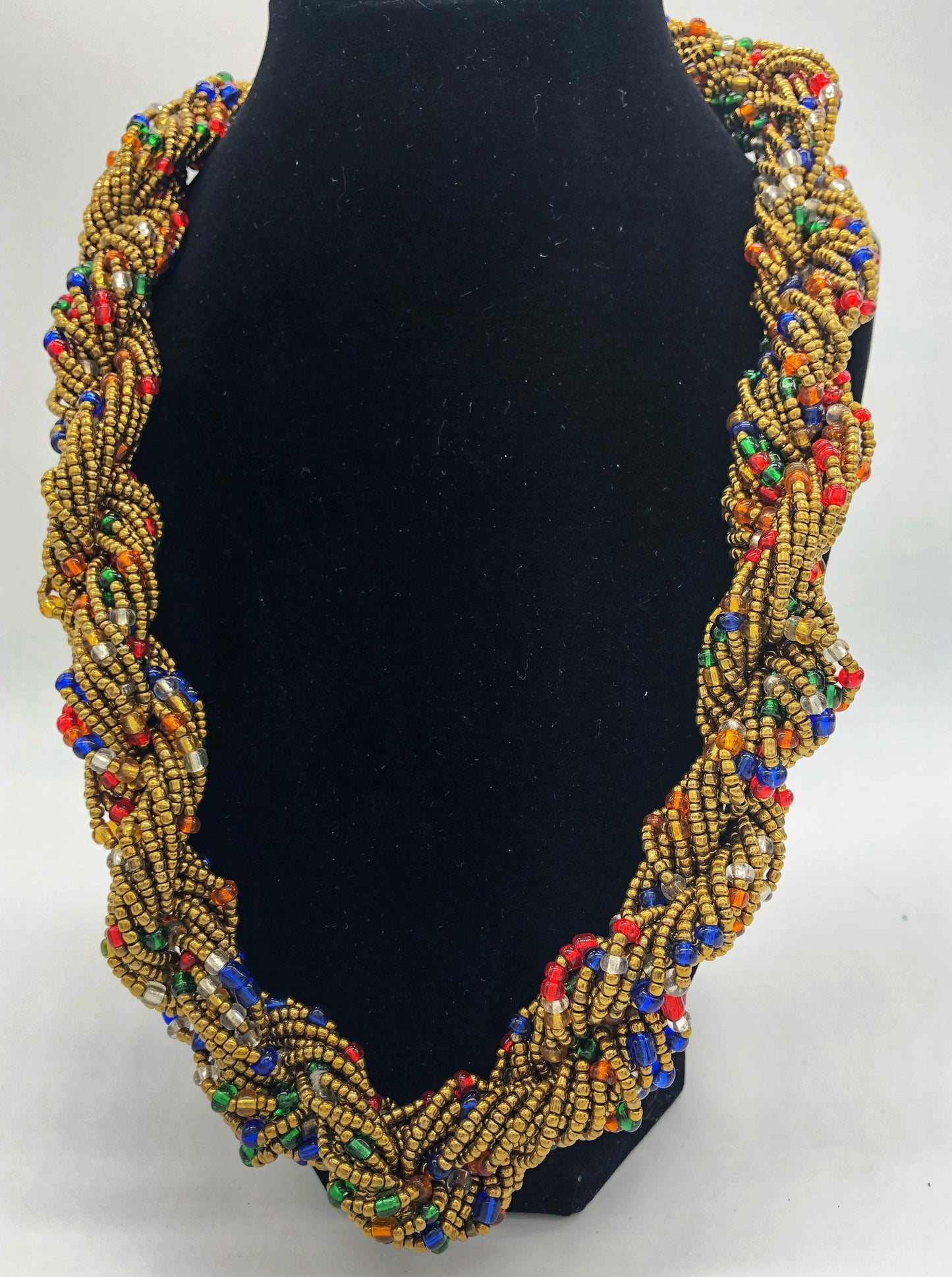 Stand out in style with this beautiful hand made braided style beaded necklace. Approximately 18" end to end. The Dorcas necklace is named after one of our ladies whose photo you will find within this collection. Gold with multi color accent