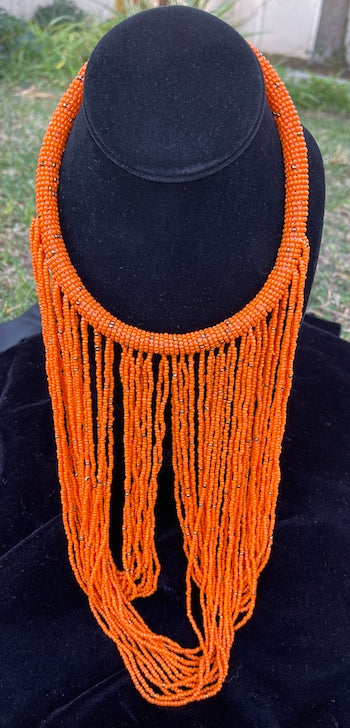 Orange necklace hanging on bust. Chocker with long strands of orange beads hanging down and looping back to connect to choker.