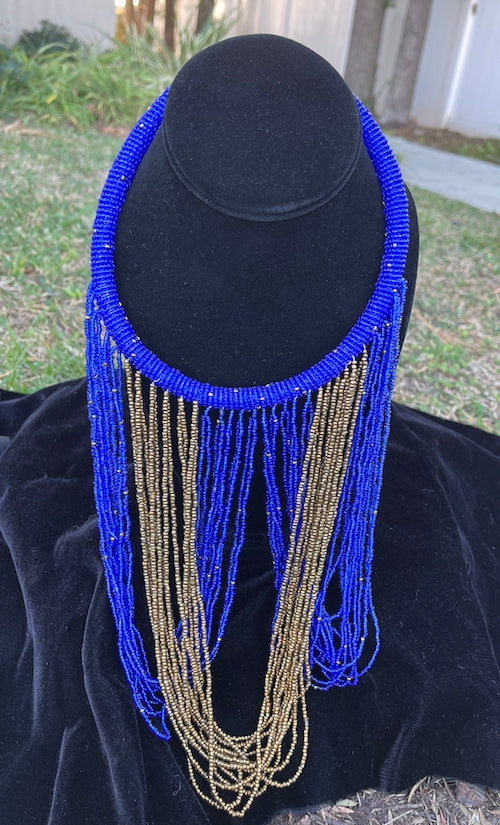Royal blue and gold necklace hanging on bust. Chocker with long strands of royal blue and gold beads hanging down and looping back to connect to choker.