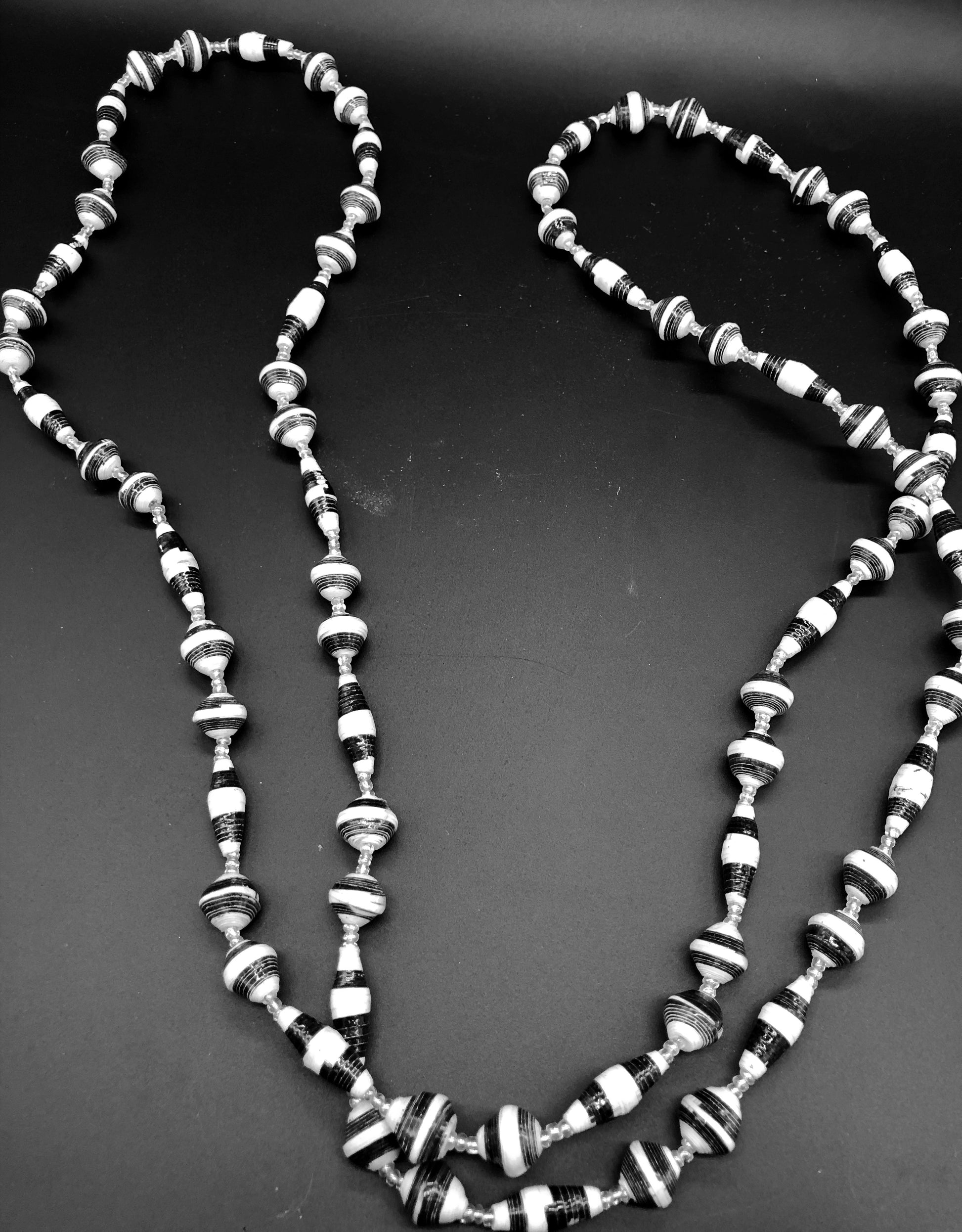 Hand crafted black and white paper bead necklace approximately 30” long with clear bead embellishment. Usually worn doubled. Each bead individually rolled by hand from magazines.  Stylish and Fashionable for casual or dressy. Fair trade.