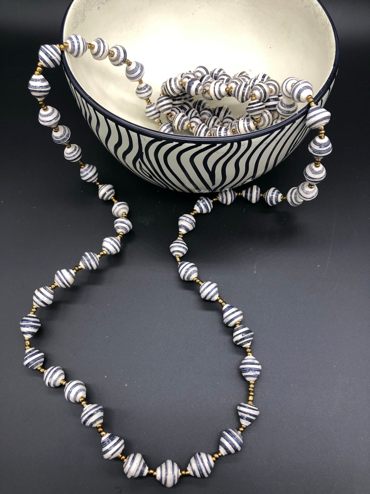 Hand crafted medium length black and white paper bead necklace and stretch bracelet set. Necklace approximately 18 inches long. Pattern is narrow white with black accent paper bead made from magazines. Each bead individually rolled by hand. Stylish and Fashionable for casual or dressy. Fair trade.