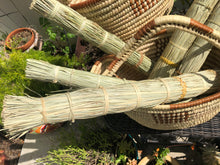 Load image into Gallery viewer, several papyrus reed brooms in a large handle basket in the garden