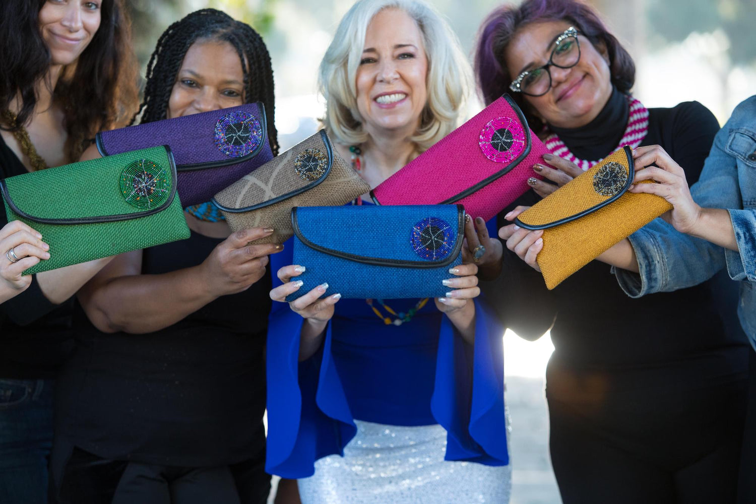 Group of women holding different color clutch purses