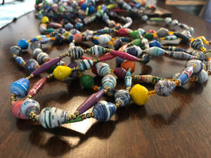 Hand made colorful long length multicolor necklace made from magazines with accent seed beads in between each hand rolled paper bead. Stylish and Fashionable for casual or dressy. Fair trade.  Approximately 33" L  Multicolor - each strand is slightly different depending on magazines used.  Includes a few solid colors as shown in photos.