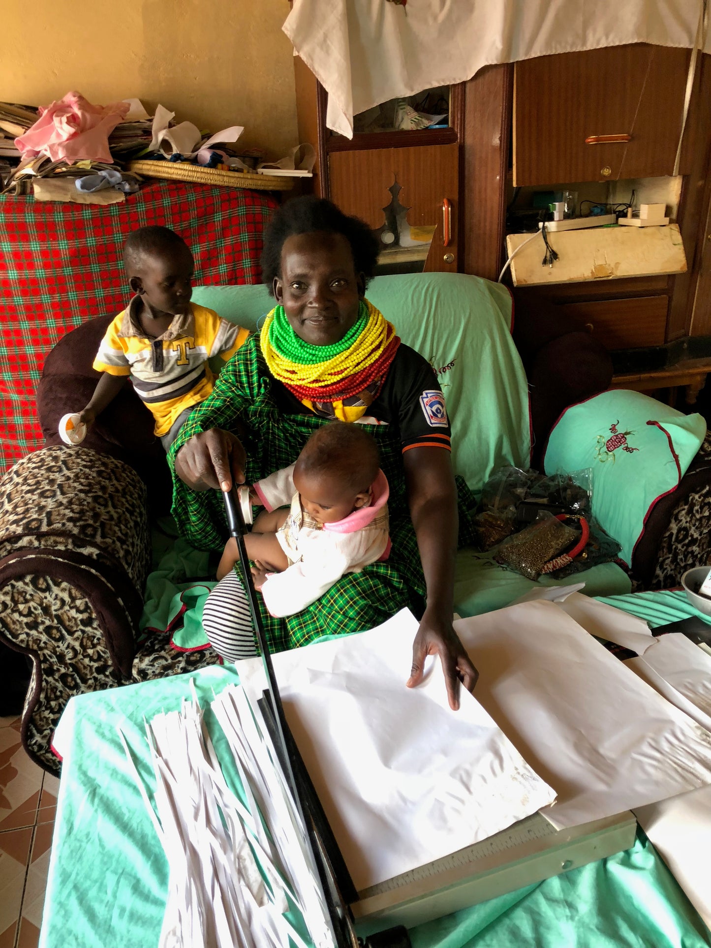 Patricia pictured cutting paper with paper cutter and 2 of her children.