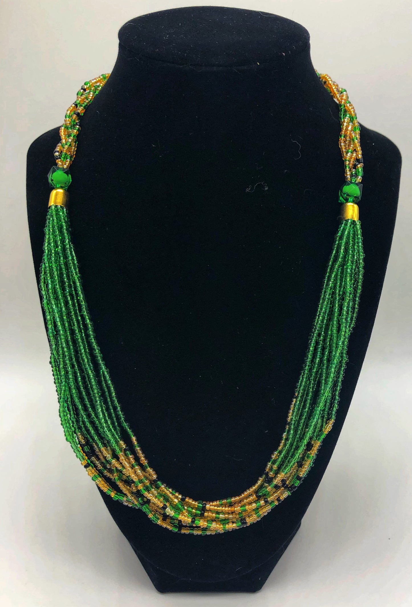 The Dinah necklace is named after one of our ladies whose photo you will find within this collection. The Dinah is a Fair trade hand crafted colorful seed bead necklace.  It is very delicate and classy.  Each necklace contains braided beads at top flowing into colorful hanging beads on the bottom. Each necklaces had solid color beads which are combined with colorful accent bead embellishment.     Slip over neck or easy open/close. Green and tan.