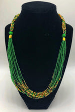 Load image into Gallery viewer, The Dinah necklace is named after one of our ladies whose photo you will find within this collection. The Dinah is a Fair trade hand crafted colorful seed bead necklace.  It is very delicate and classy.  Each necklace contains braided beads at top flowing into colorful hanging beads on the bottom. Each necklaces had solid color beads which are combined with colorful accent bead embellishment.     Slip over neck or easy open/close. Green and tan.