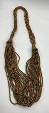 Load image into Gallery viewer, Make a statement with this beautiful handmade seed bead necklace.  Styled with braided beads around the neck flowing into a loose styled design.  Gold with orange bead accent