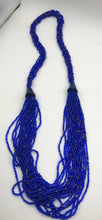 Load image into Gallery viewer, Make a statement with this beautiful handmade seed bead necklace.  Styled with braided beads around the neck flowing into a loose styled design.  Royal blue with gold bead accent