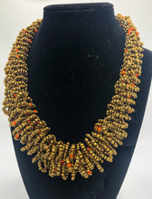 Load image into Gallery viewer, Stand out in style with this beautiful handmade loop bead style necklace.  Hover over the photo to see the detail of how the beads are made into a loop design.  Thoughtfully designed for style and stand out fashion. Approximately 18&quot; end to end.  Gold with orange accent beads