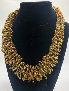 Stand out in style with this beautiful handmade loop bead style necklace.  Hover over the photo to see the detail of how the beads are made into a loop design.  Thoughtfully designed for style and stand out fashion. Approximately 18" end to end.  Gold with orange accent beads