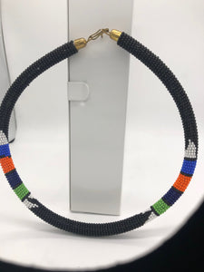 Wear the epitome of Kenya style with The Bintiah necklace.  This necklace is handmade using colorful seed beads that are intricately and tightly wrapped around a solid piece fo make a stunning statement with any outfit.   Black with colorful bead accent. 