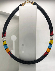 Wear the epitome of Kenya style with The Bintiah necklace.  This necklace is handmade using colorful seed beads that are intricately and tightly wrapped around a solid piece fo make a stunning statement with any outfit.   Black with colorful bead accent. 