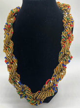 Load image into Gallery viewer, Stand out in style with this beautiful hand made braided style beaded necklace.  Approximately 18&quot; end to end.   The Dorcas necklace is named after one of our ladies whose photo you will find within this collection. Gold with multi color accent