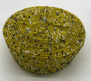 Fair Trade hand crafted basket made from seed beads. Round shape with lid. These baskets take 1 full day to create.  yellow gold, black and white accent beads.