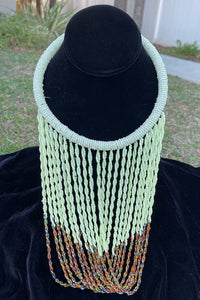 Cream color with multi color ends necklace hanging on bust. Chocker with long strands of cream color with multi color on end beads hanging down and looping back to connect to choker.