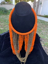 Load image into Gallery viewer, Orange and gold necklace hanging on bust. Chocker with long strands of orange and gold beads hanging down and looping back to connect to choker.