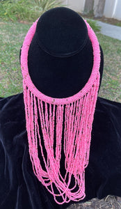 Pink necklace hanging on bust. Chocker with long strands of pink beads hanging down and looping back to connect to choker.