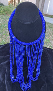 Royal blue necklace hanging on bust. Chocker with long strands of royal blue beads hanging down and looping back to connect to choker.