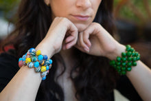 Load image into Gallery viewer, Woman propping hands up on chin wearing a multi color bead on one wrist and a green bracelet on the other