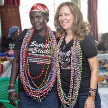 Load image into Gallery viewer, 2 women standing and wearing strands of long paper beads in multiple colors also wearing baskets and beads t-shirts 