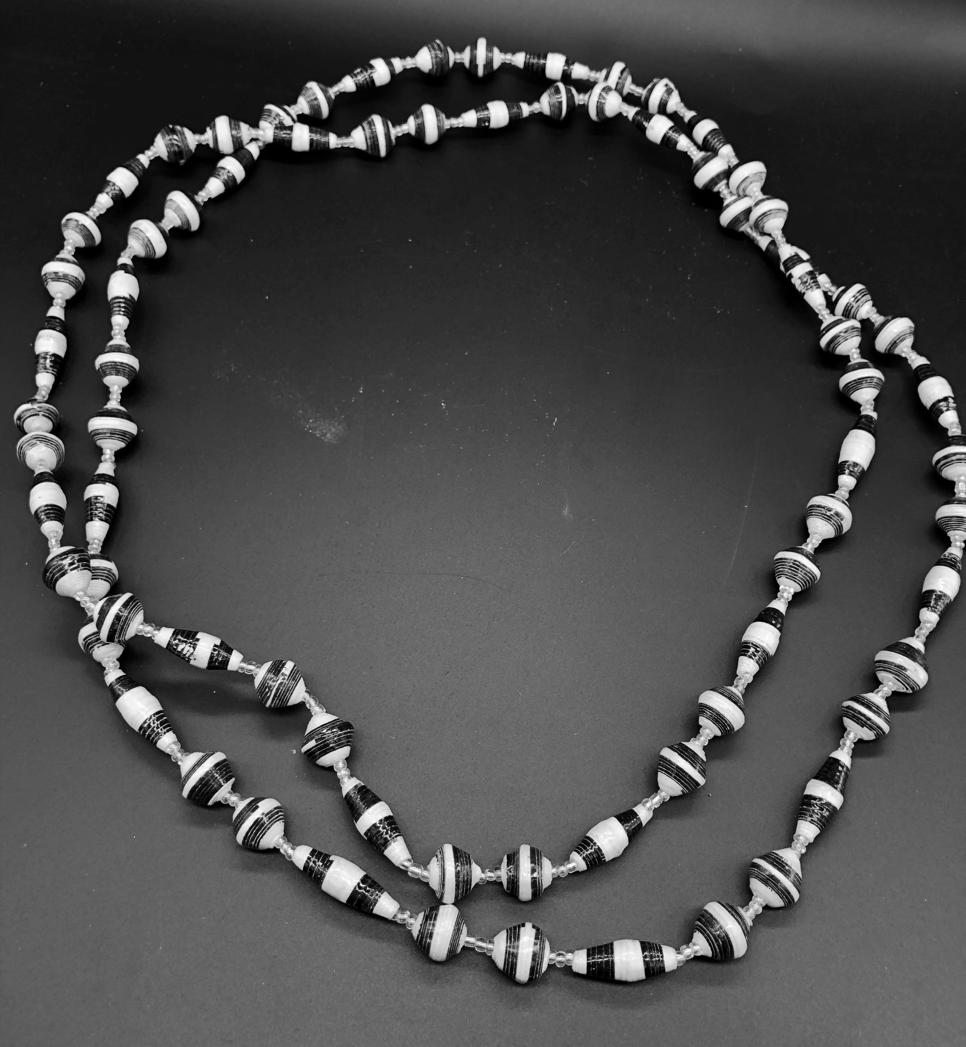 Hand crafted black and white paper bead necklace approximately 30” long with clear bead embellishment. Usually worn doubled. Each bead individually rolled by hand from magazines.  Stylish and Fashionable for casual or dressy. Fair trade.  