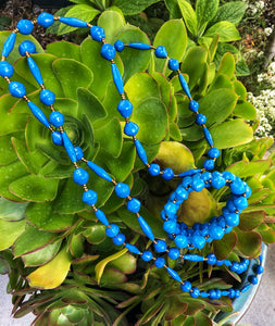 Long handmade paper bead necklace and stretch or memory wrap bracelet set blue color. Necklace is approximately 30” long and usually worn doubled. Bracelet is a wrap bracelet. Handcrafted from magazines. Fair trade. solid blue necklace and stretch bracelet pictured