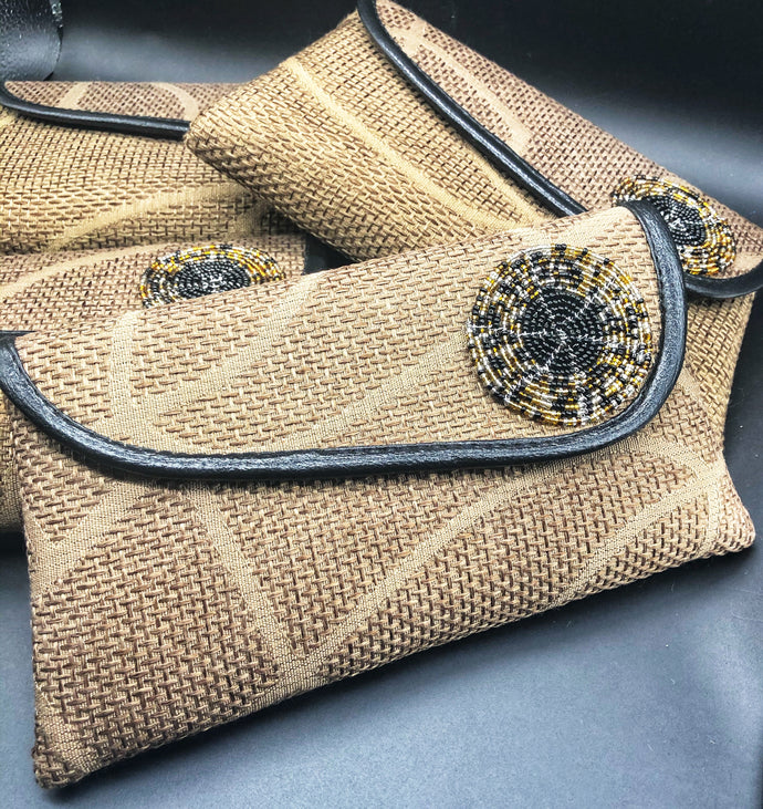 light brown clutches leaning on each other. giraffe style lines and round bead on flap  