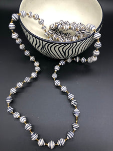 Hand crafted medium length black and white paper bead necklace and stretch bracelet set. Necklace approximately 18 inches long. Pattern is narrow white with black accent paper bead made from magazines. Each bead individually rolled by hand.  Stylish and Fashionable for casual or dressy. Fair trade.  