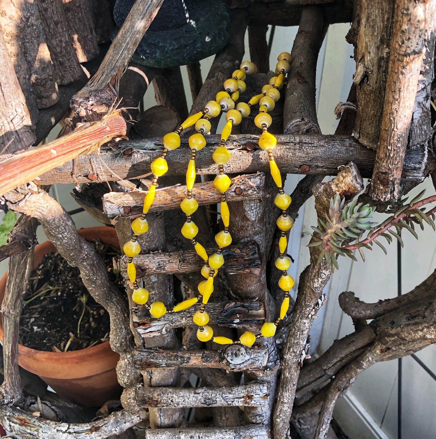 Long handmade paper bead necklace and stretch bracelet set weathered yellow color. Necklace is approximately 30” long and usually worn doubled. Bracelet is a stretch bracelet. Handcrafted from magazines. Fair trade. Color Yellow stretch bracelet and necklace pictured 