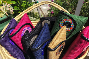 large basket with several clutch purses arranged inside red, beige, green, blue, pink, purple