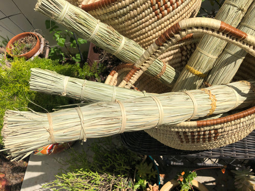 several papyrus reed brooms in a large handle basket in the garden